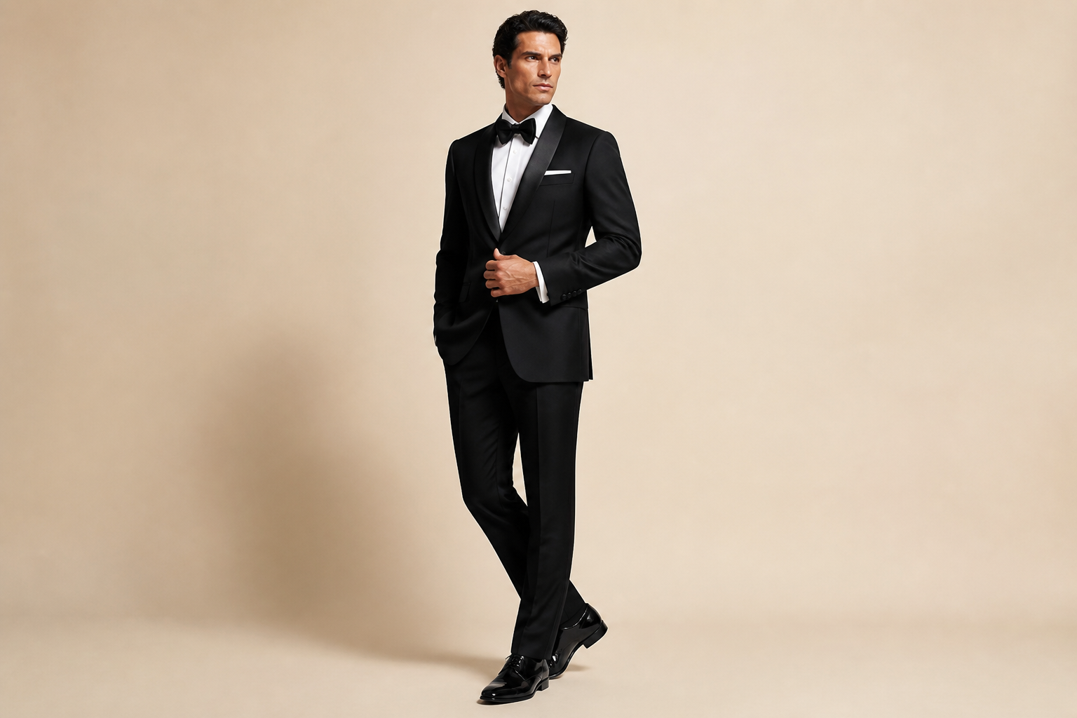 Black shawl-lapel tuxedo on light beige studio.